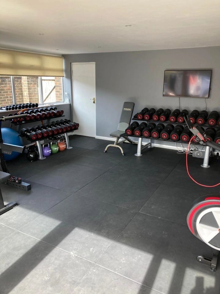 The other end of the gym: dumbbell rack, gym balls and a wall-mounted screen.