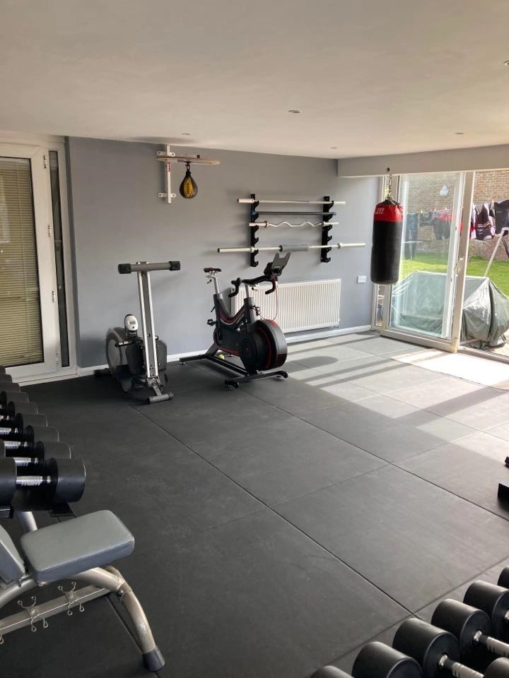 The gym: spin bike, punchbag, bench and dumbbells, with patio doors letting in daylight.